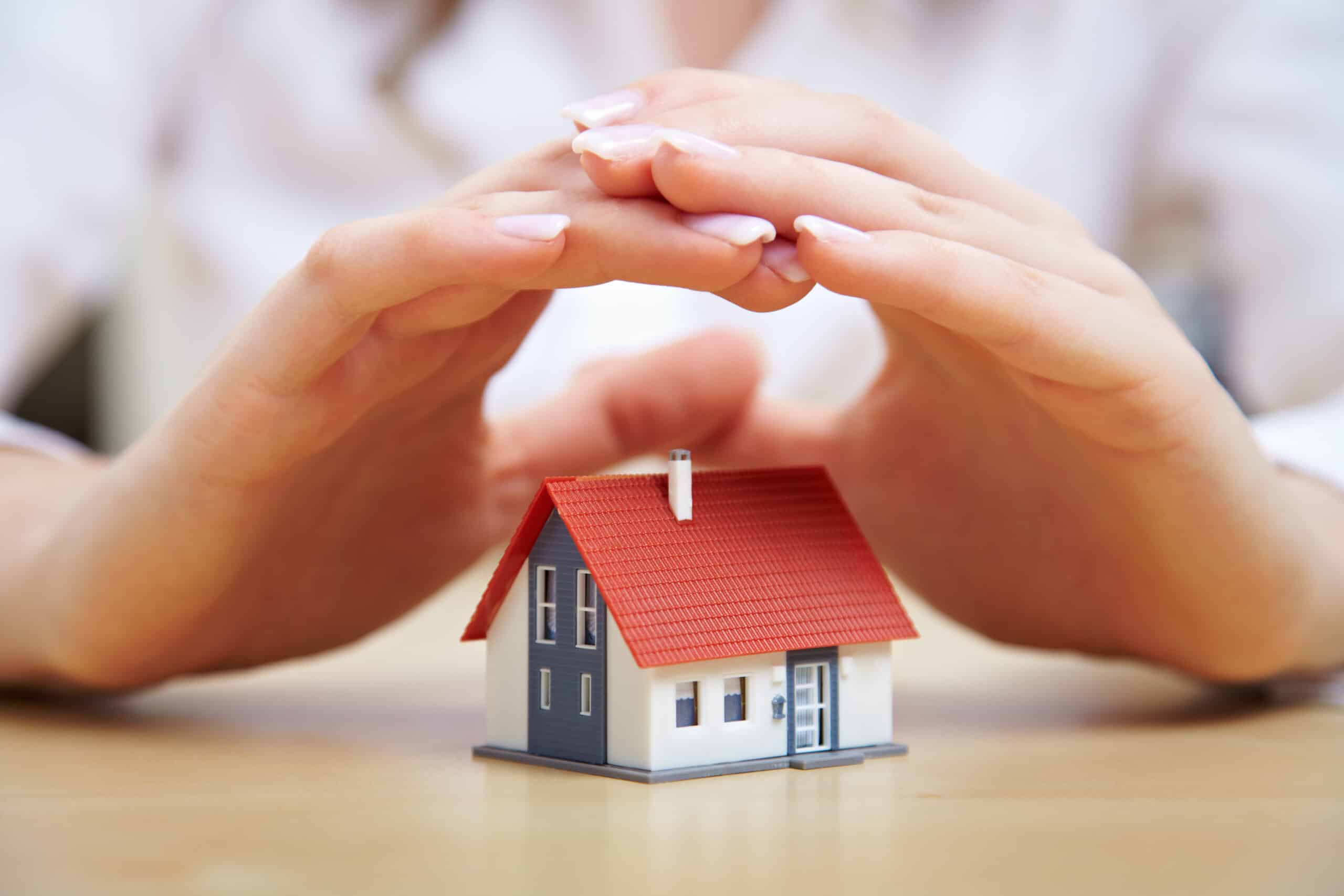 Female hands protecting small house