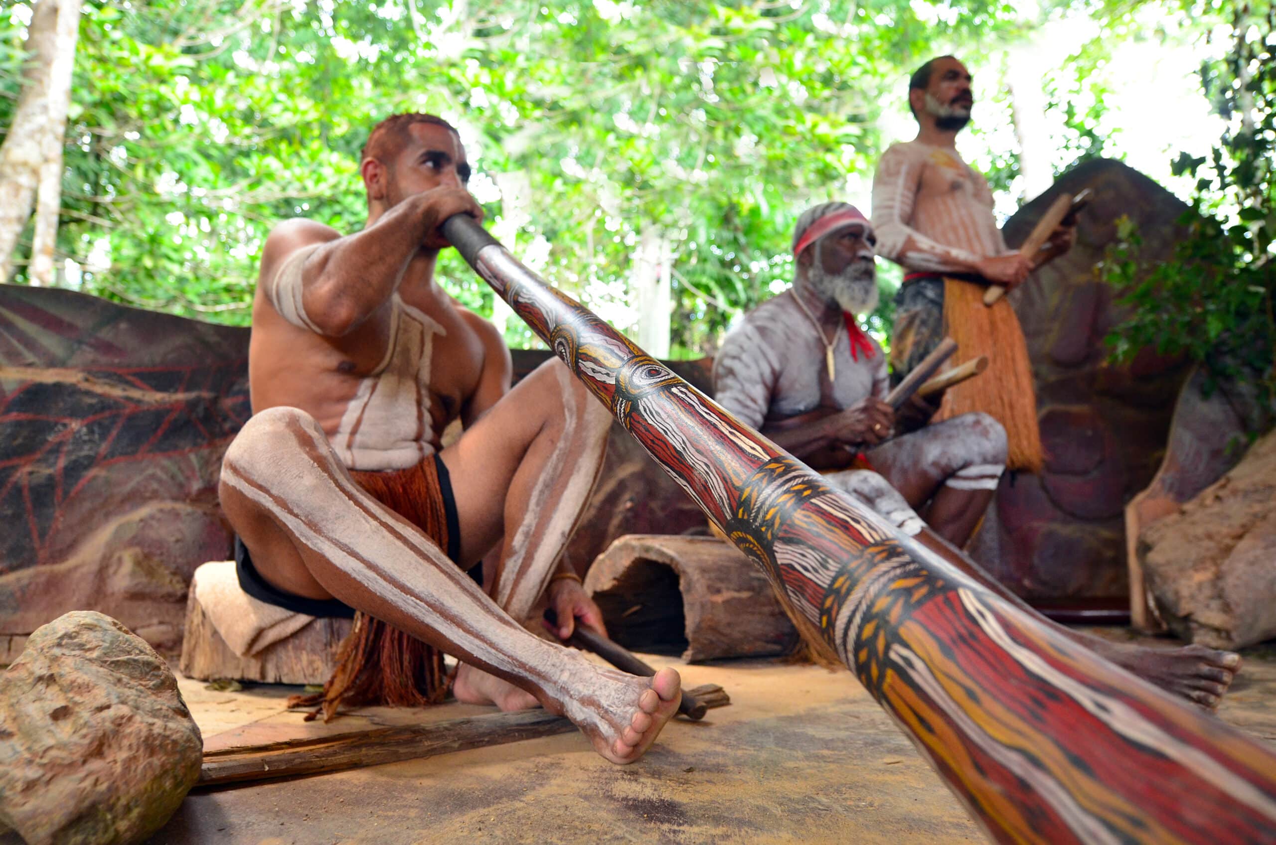 Australian Aboriginal men play Aboriginal music on didgeridoo and wooden instrument during Aboriginal culture show